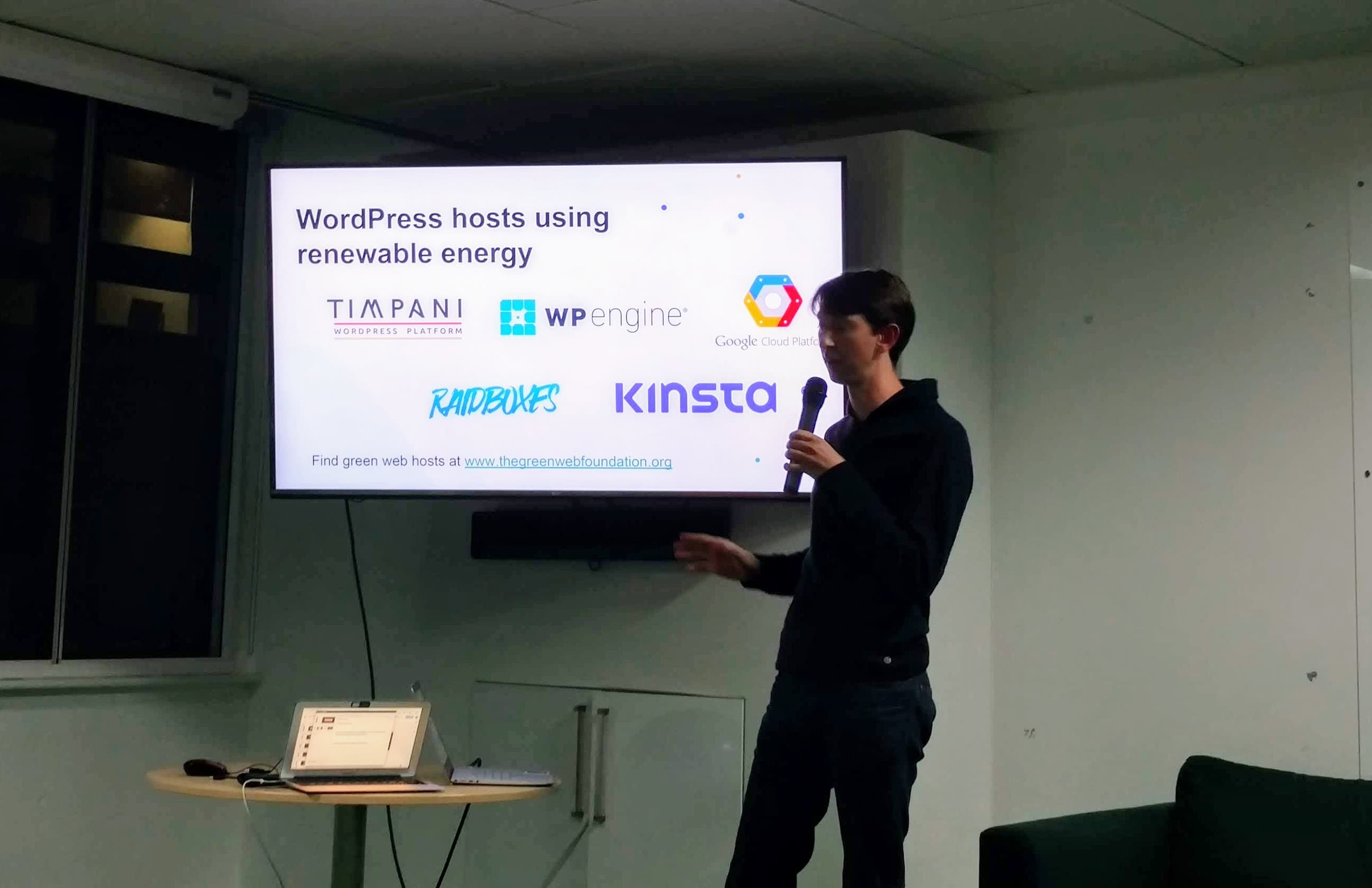 Tom Greenwood presenting at WPLDN in front of a slide showing green WordPress hosts including Kinsta, Timpani, Raidboxes, WP Engine and Google Cloud Platform